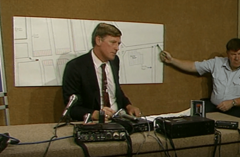 Inspector Dannye Moloney informs the media about a suspect Holden Commodore Vacationer sedan seen behaving suspiciously in Bayswater soon before Sharon Wills was dumped at Bayswater High School.  An unknown police officer points out the location of the near collision on a map.