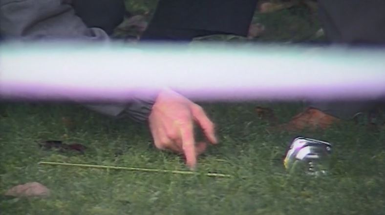 A detective measures something on the grass at the electricity substation in Tennyson Street, Kew where Nicola Lynas was dumped at 2am on 6 July 1990.